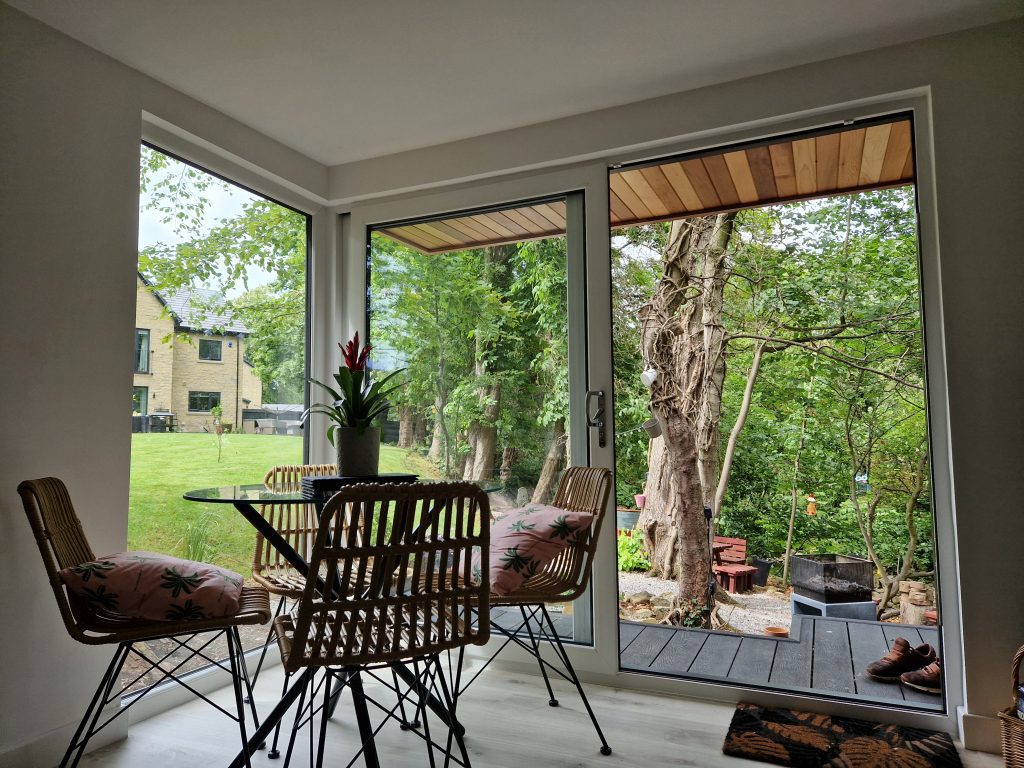 Garden room interior with dining furniture and open glass doors overlooking the garden