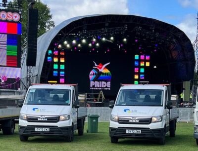 Two Lili Waste vehicles and waste bins in front of an outdoor event stage