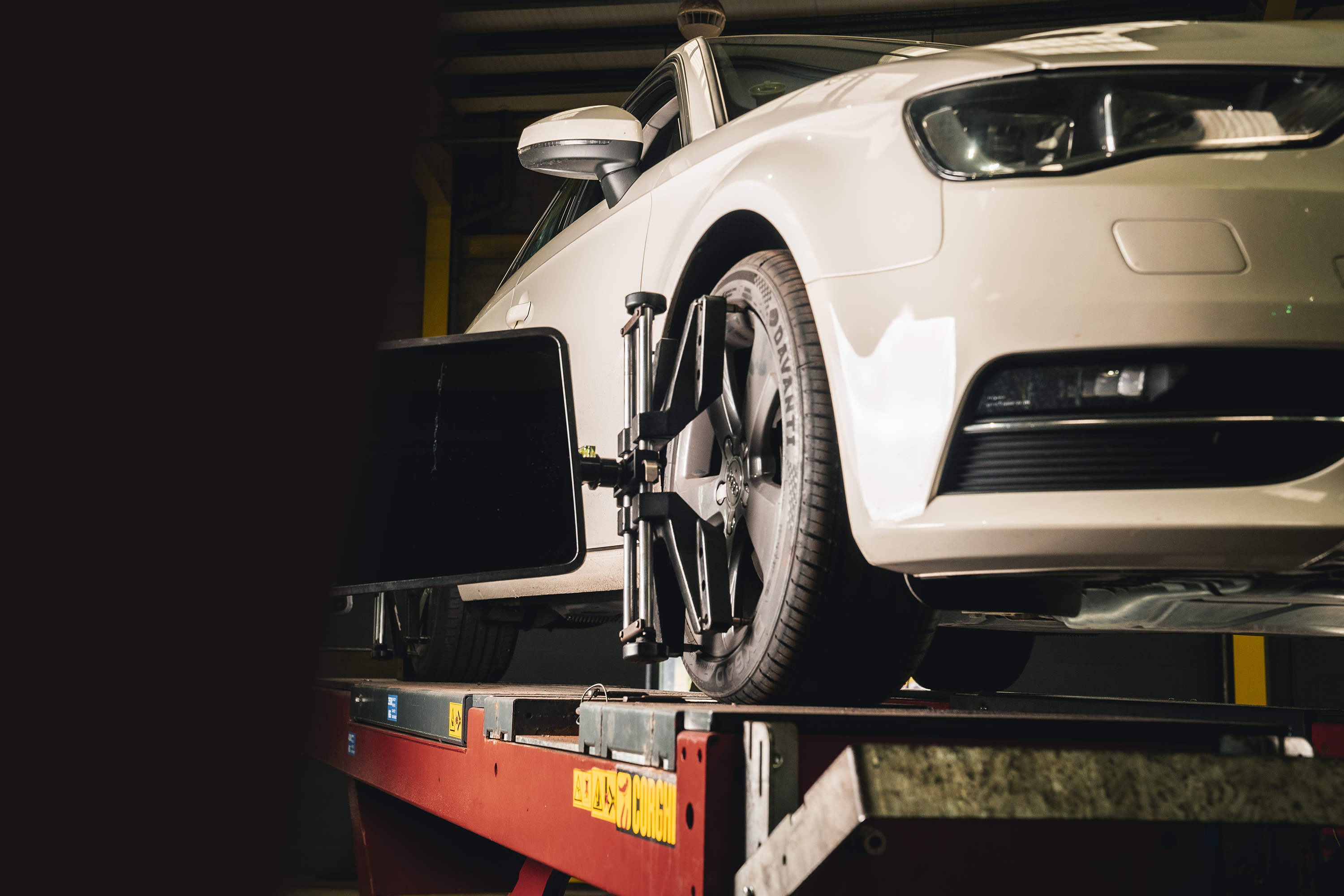 White Volkswagen on wheel-alignment equipment in a vehicle workshop