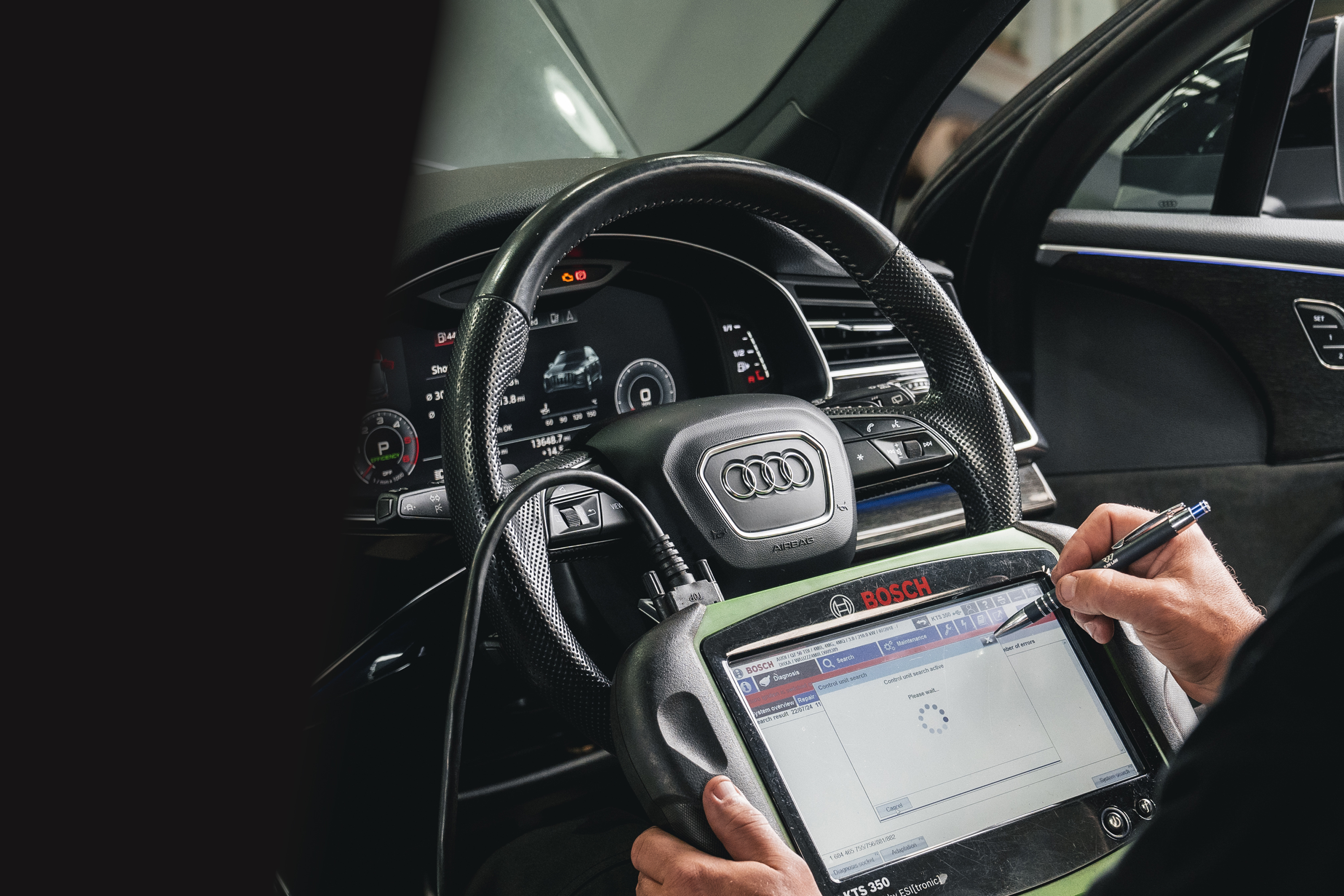 Technician using a diagnostic tablet inside an Audi