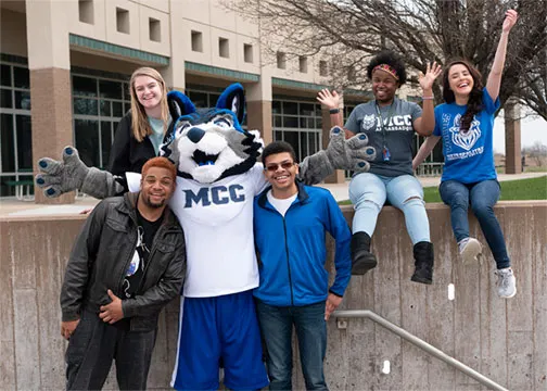 Estudiantes y la mascota Wolves frente a un edificio de Maple Woods