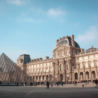 Participantes visitan los exteriores del Louvre durante un free tour de SANDEMANs en París