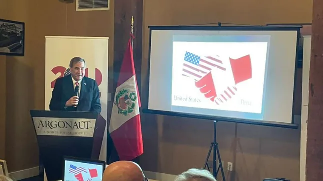 Representante del Consulado del Perú en San Francisco en un acto cultural junto a la bandera peruana