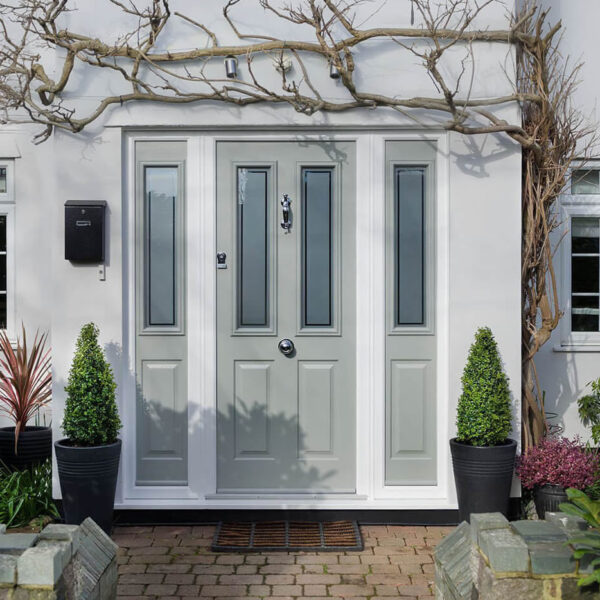 Grey front door with glass panels and two side windows on a white facade.