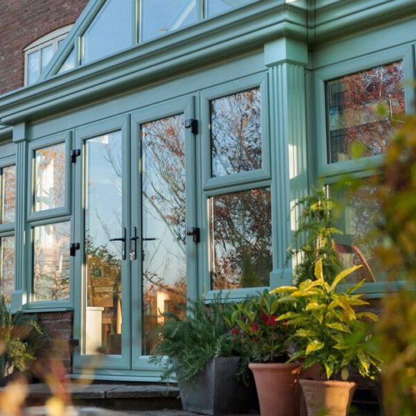 Conservatory with green frames and large glass windows and doors.