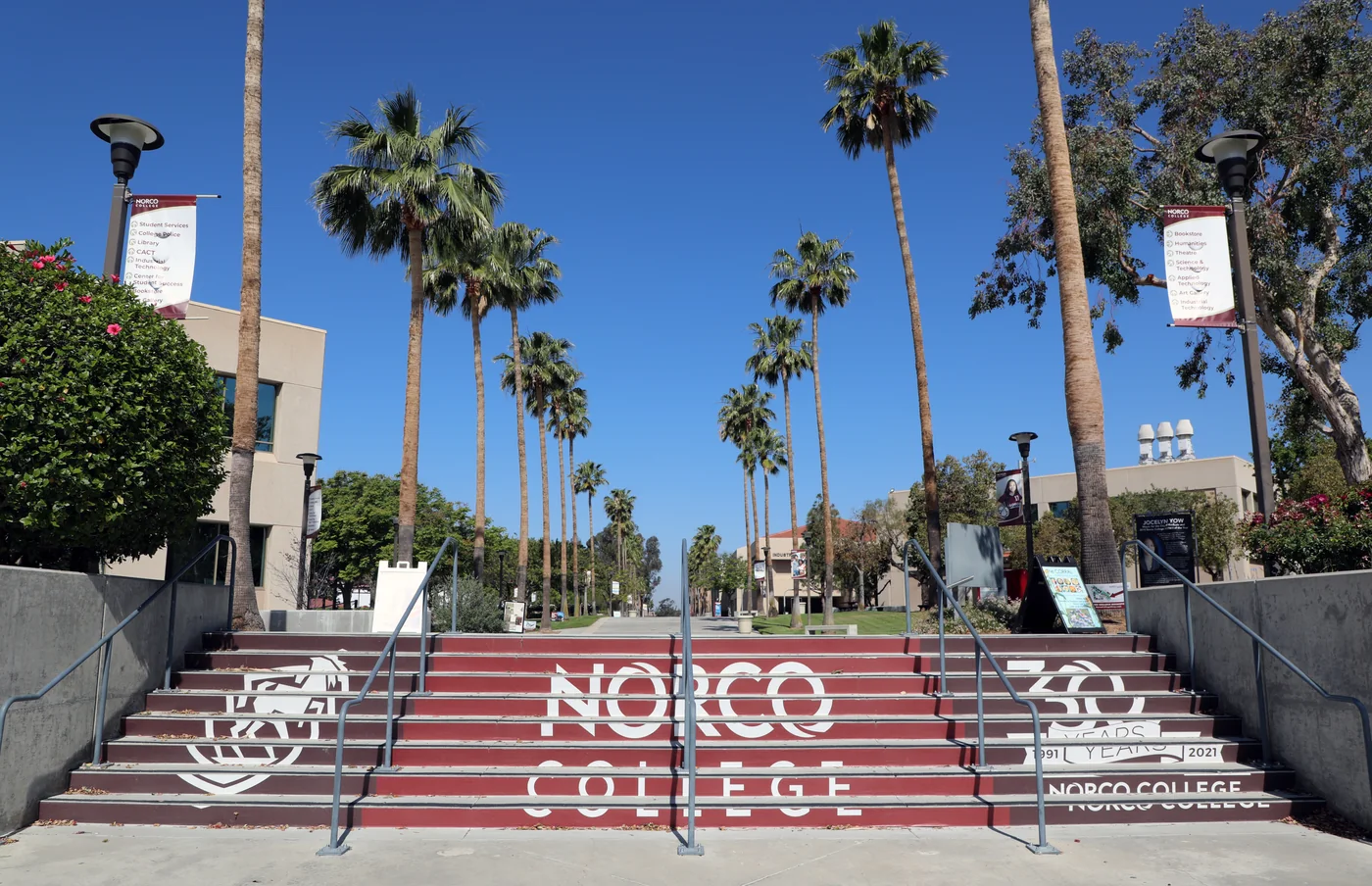 Escalinata principal y edificios del campus de Norco College, con palmeras y señalización de la institución.
