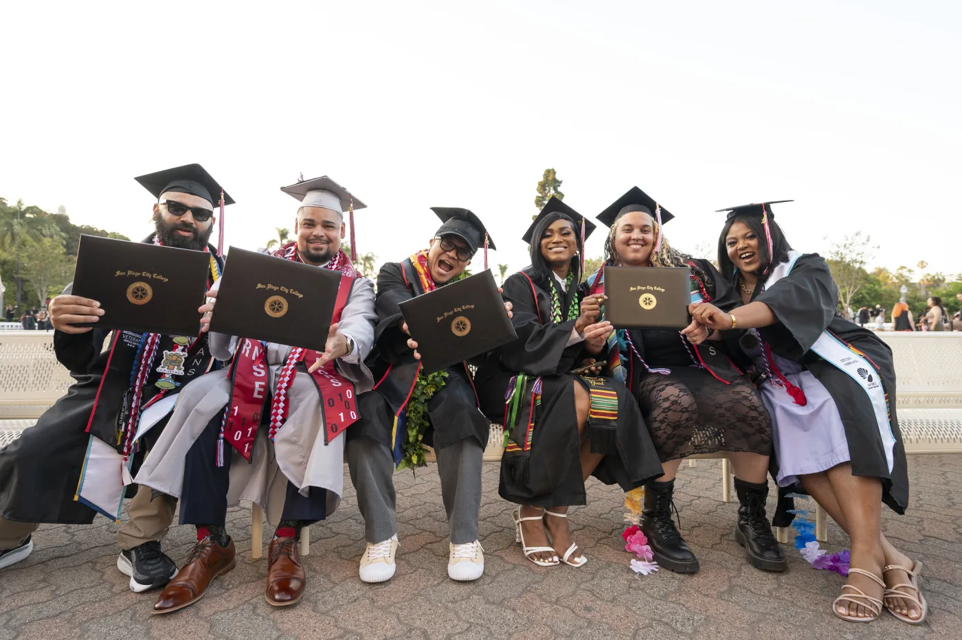 Estudiantes graduados de San Diego City College con toga y birrete durante una ceremonia.