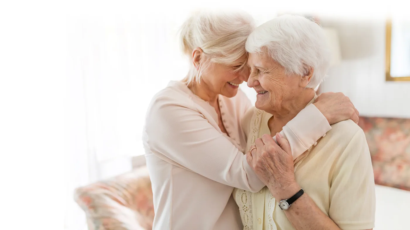Una cuidadora acompana a una mujer mayor en una fotografia del sitio de Resources for Seniors.