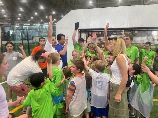 Jugadores, entrenadores y voluntarios se reúnen en un círculo durante TOPSoccer.