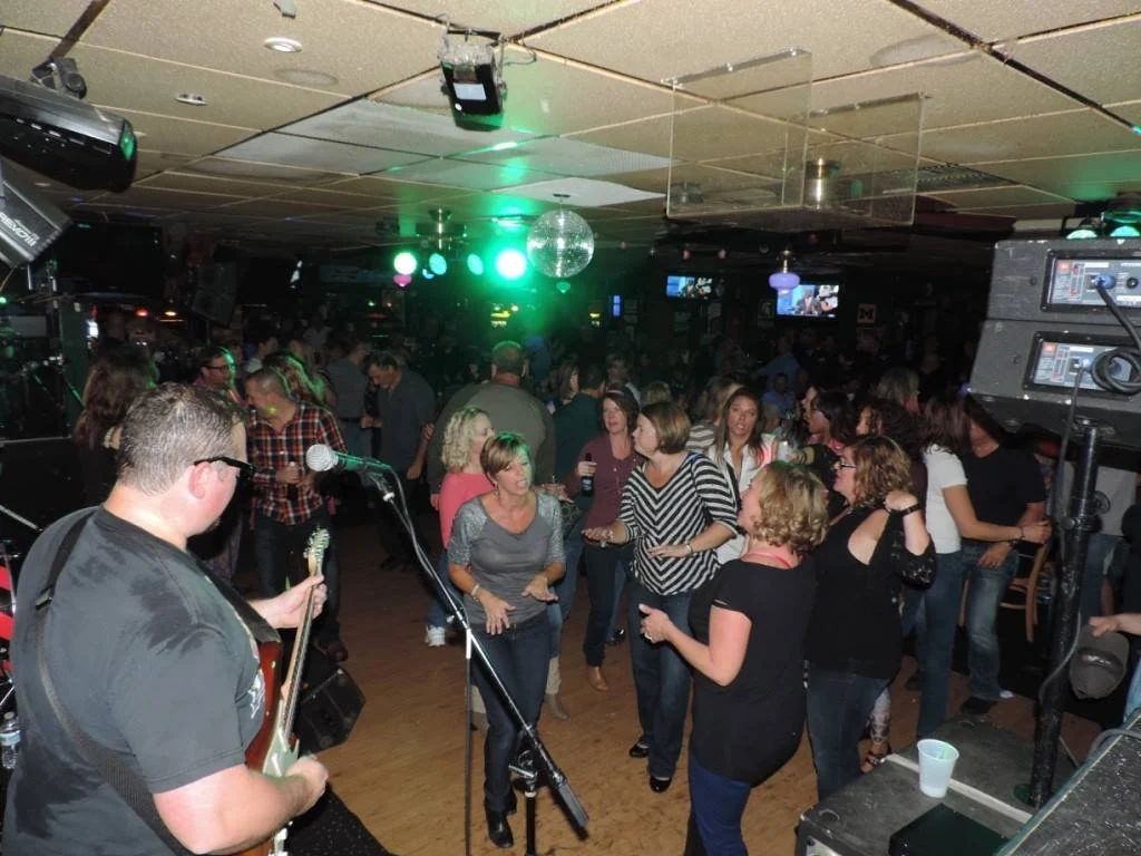 Público y músico durante una noche de entretenimiento en Sherman’s Lounge Source: https://shermanslounge.com/wp-content/uploads/2016/09/dancing1.jpg