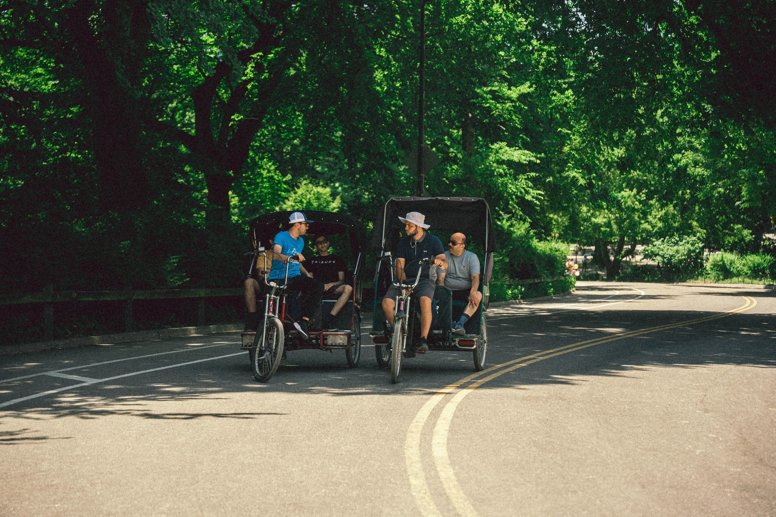Pedicabs de Wander NYC avanzan por un camino arbolado de Central Park