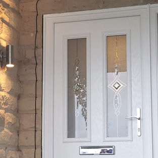 Puerta exterior blanca con paneles de vidrio instalada en una vivienda.