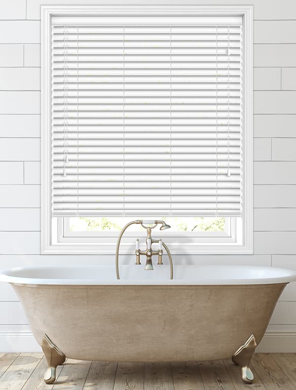 Persiana veneciana blanca instalada sobre una bañera.