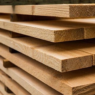 Tablas de madera apiladas, con los cantos y vetas visibles.