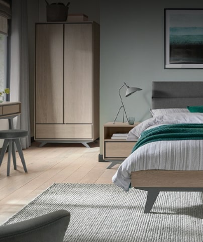 Dormitorio amueblado con cama, armario y mesa auxiliar.