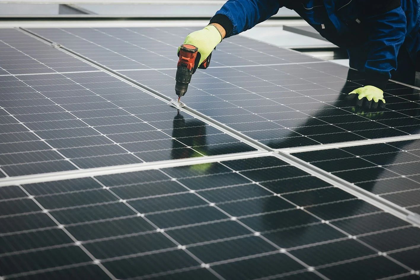 Una persona trabaja en un sistema de paneles fotovoltaicos / A worker services a photovoltaic panel system.