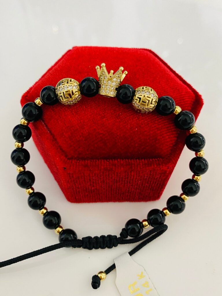 Pulsera artesanal de cuentas y cordón sobre un cojín rojo / Handmade beaded bracelet and cord on a red display cushion