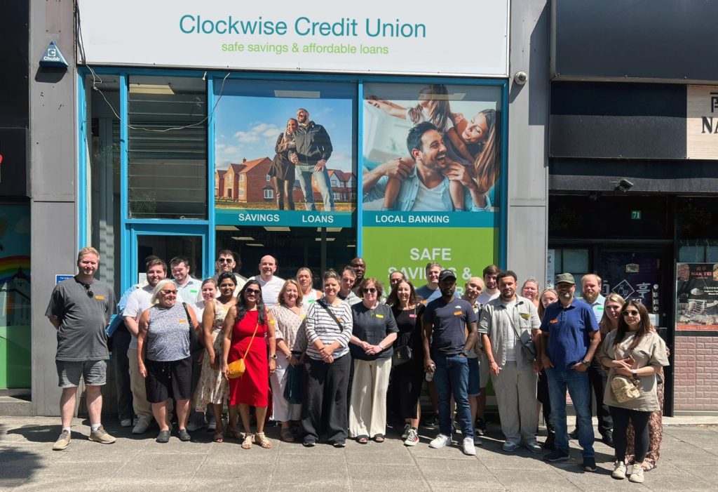 Fachada de una sucursal de Clockwise Credit Union con miembros y personal / Clockwise Credit Union branch with members and staff