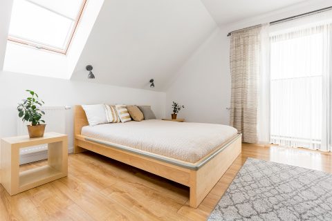 Bedroom showroom display with a light-wood bed and neutral linens.
