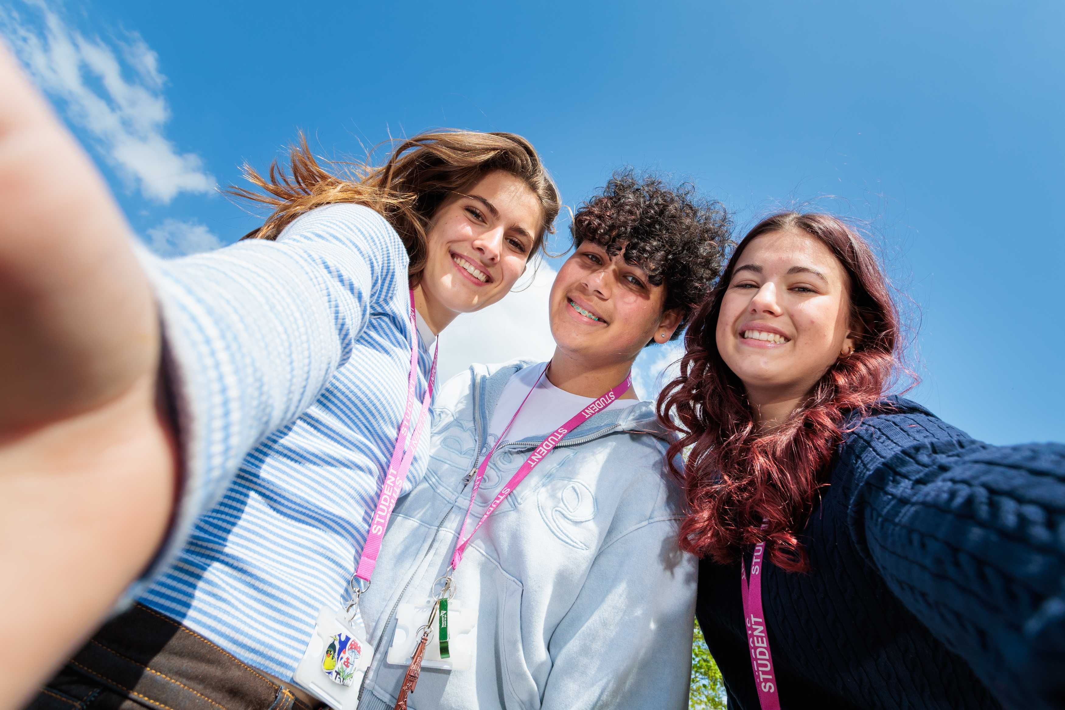 Three young people wearing event lanyards outdoors