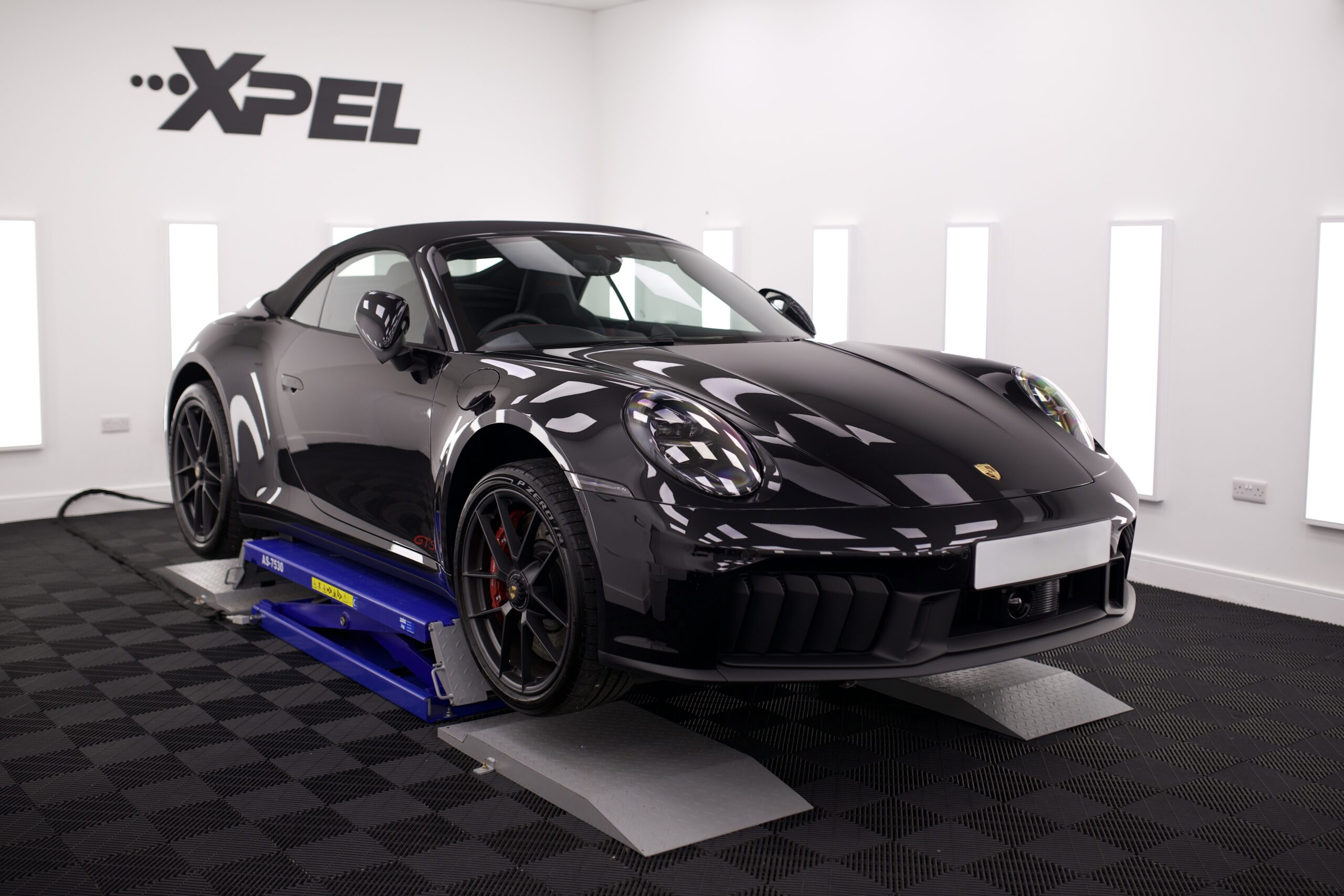 A sports car undergoing paint protection film installation.