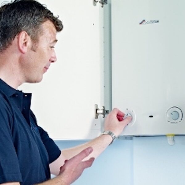A technician checks a wall-mounted home heating unit