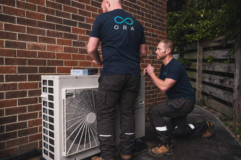 ORA Renewables technicians installing an outdoor heat pump unit