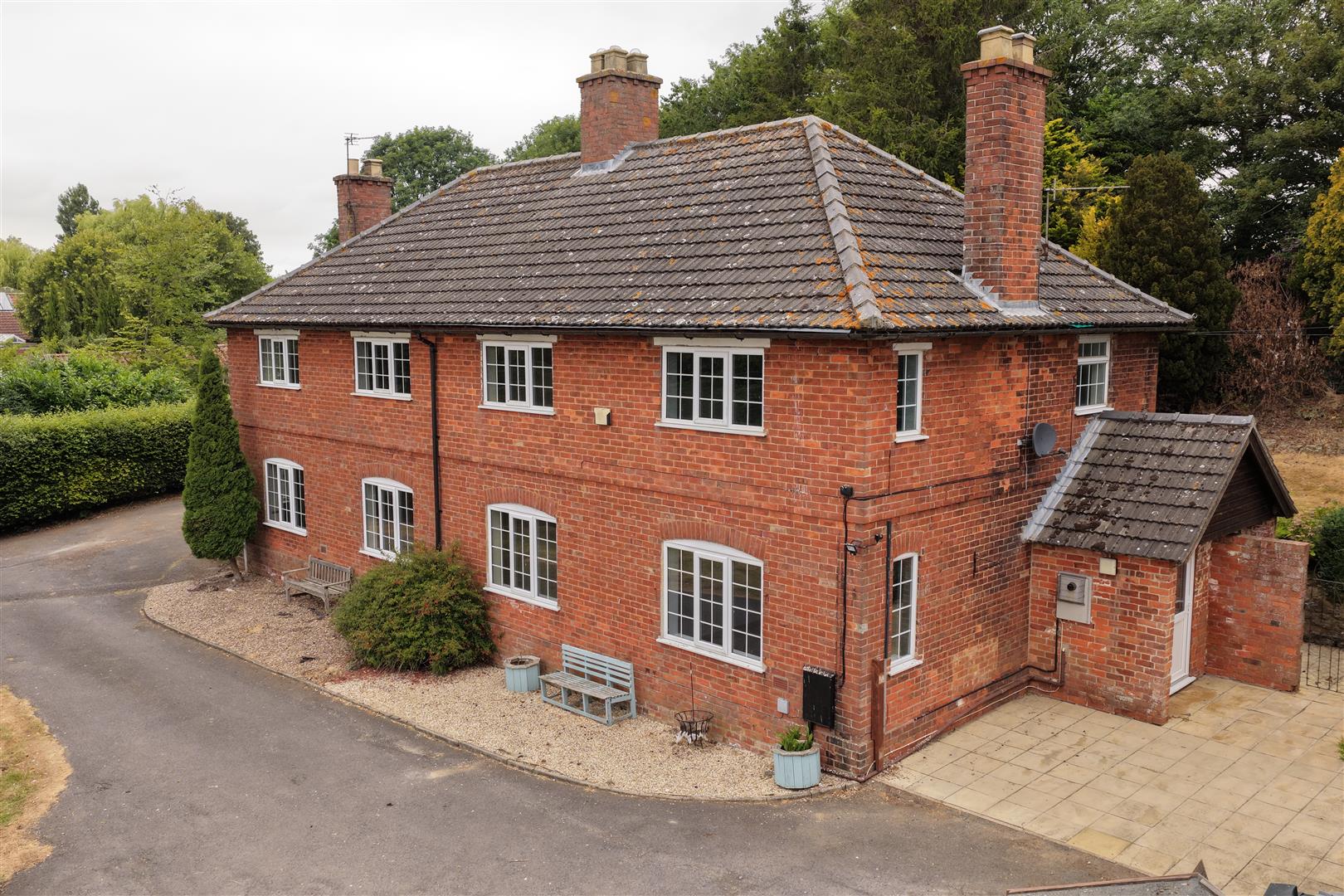 Brick country house set back behind a driveway and lawn.