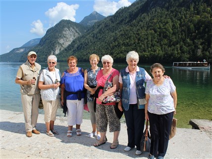 A group of travelers standing together beside a lake.