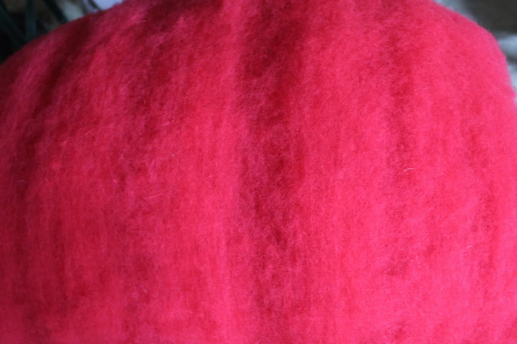 Bright red wool fiber shown in close-up.