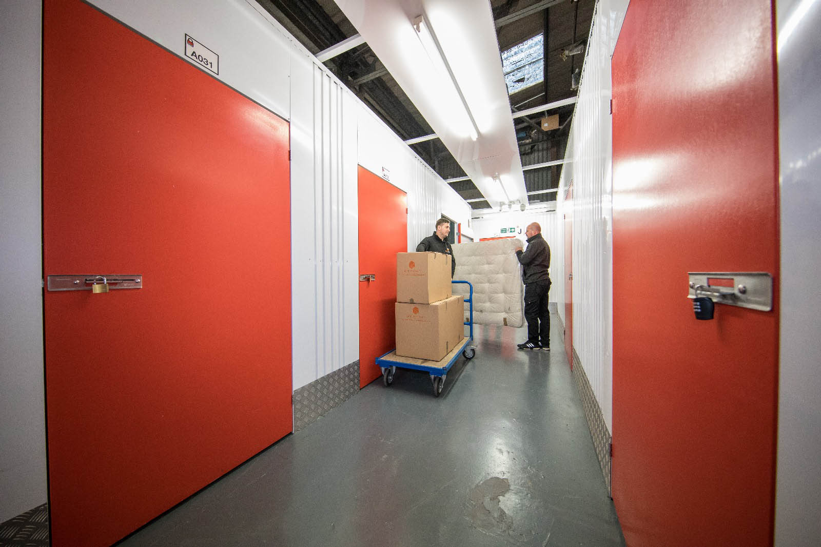 A moving team transporting belongings through a storage corridor.