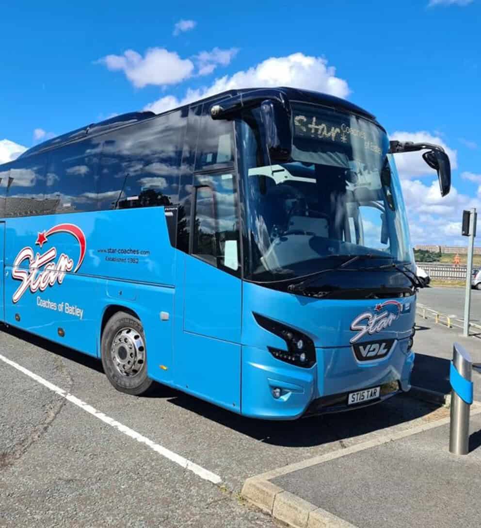 A blue Star Coaches touring coach parked outdoors.