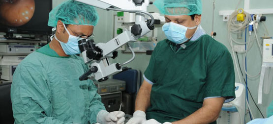 Medical team using a surgical microscope during a procedure.