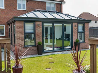 Conservatory addition with glass roof and glazed doors at a brick home
