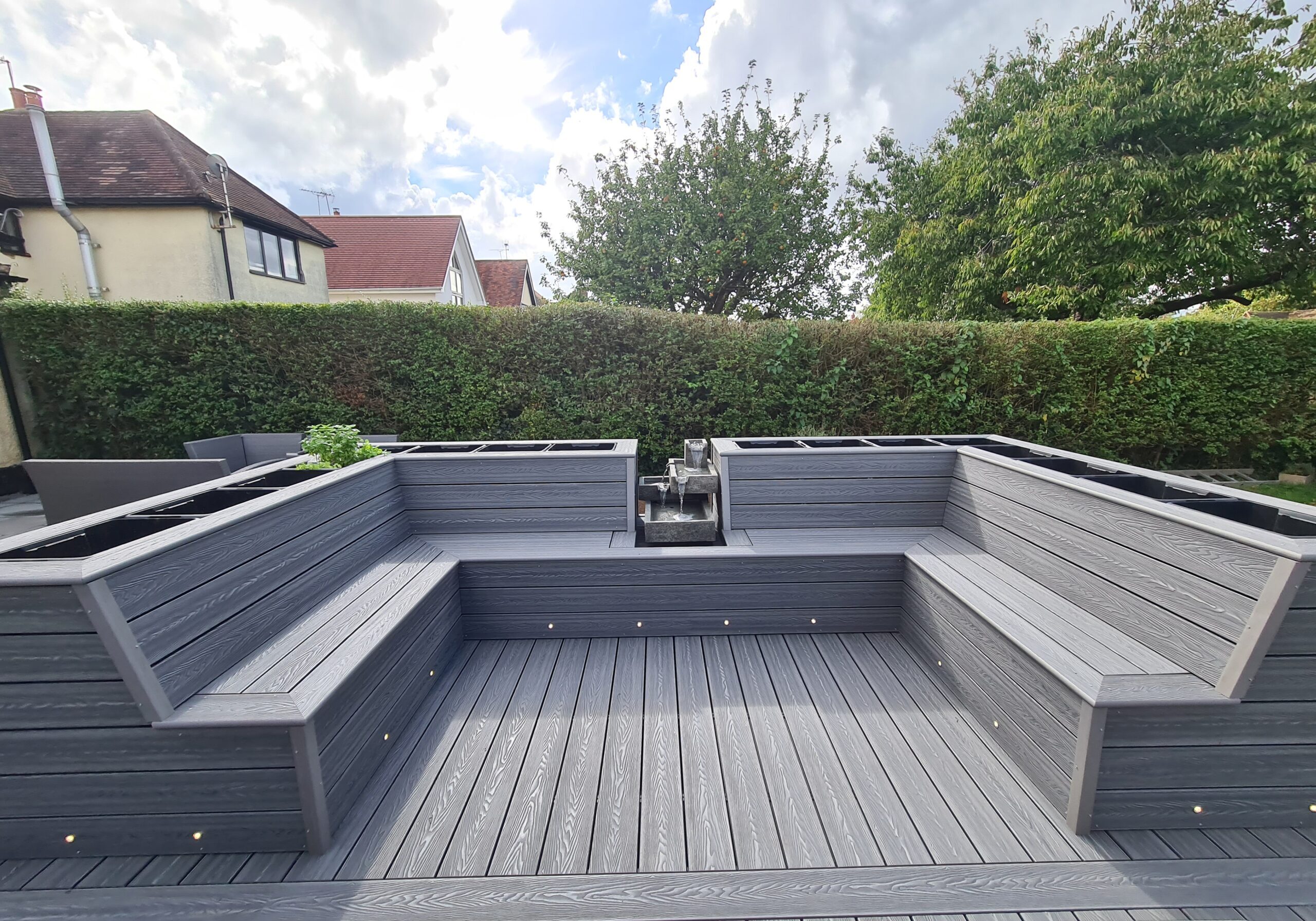Finished gray composite deck with built-in raised seating and garden planters