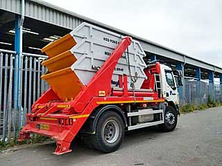Hughes Waste roll-on roll-off skip truck at an industrial site
