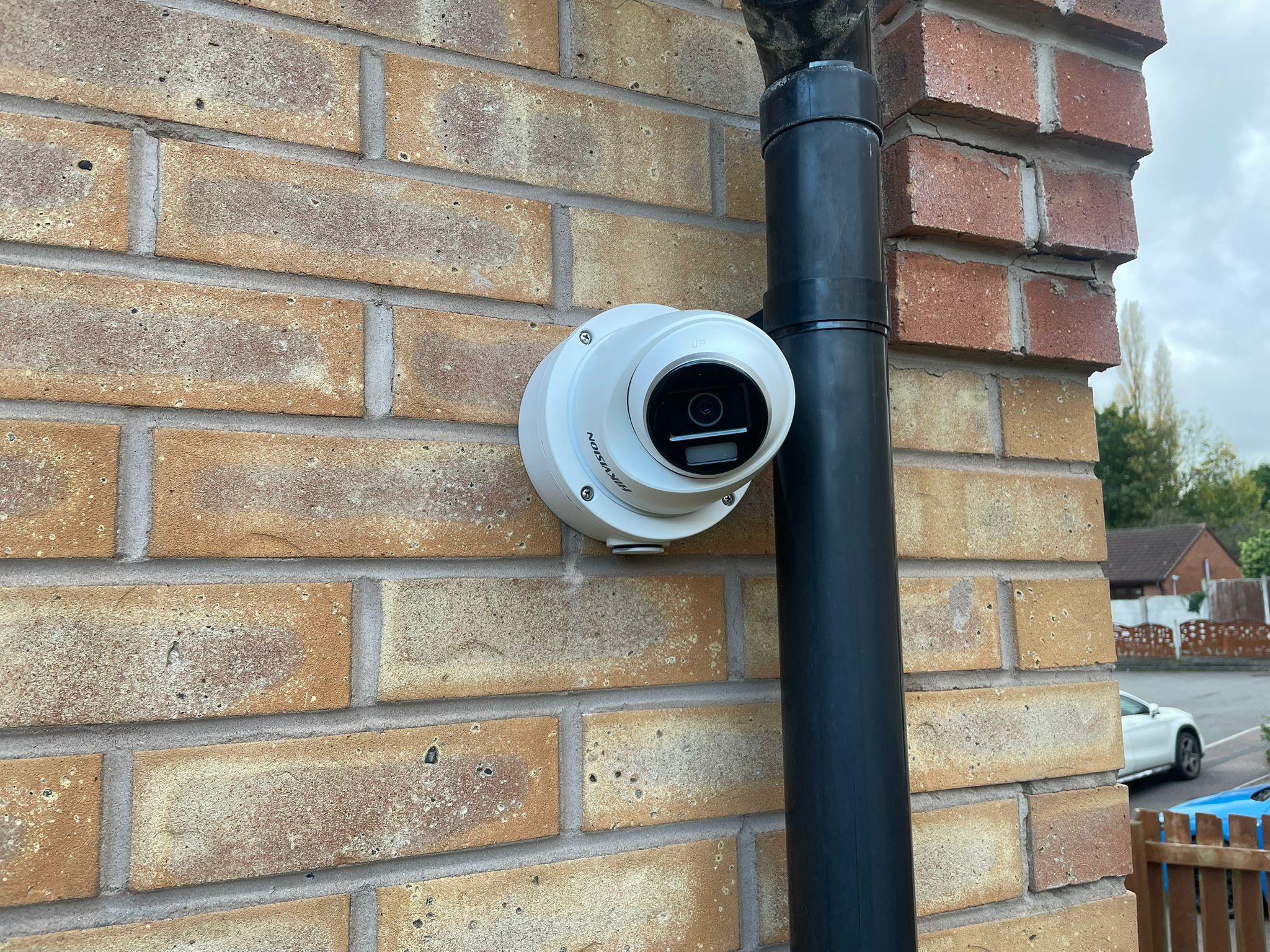 A white security camera installed on the outside of a home
