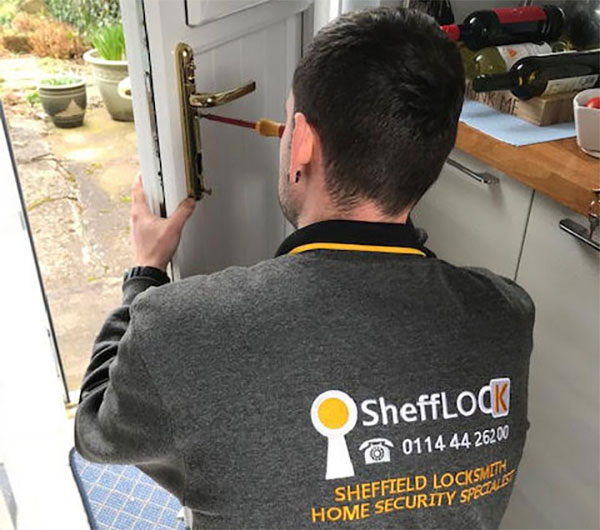A locksmith working on a door lock at a home
