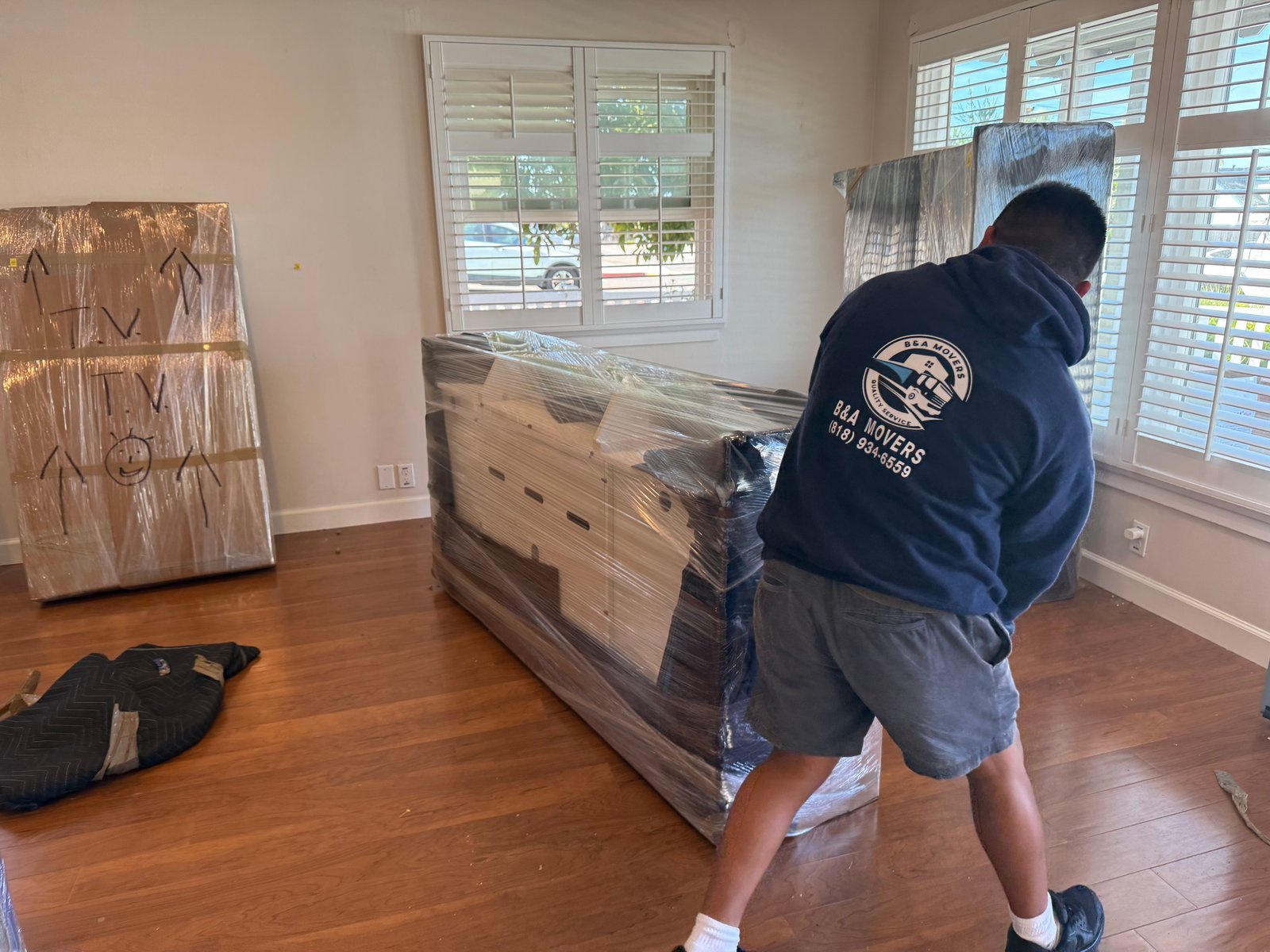 Trabajador de mudanza envolviendo un mueble antes de trasladarlo en una vivienda.