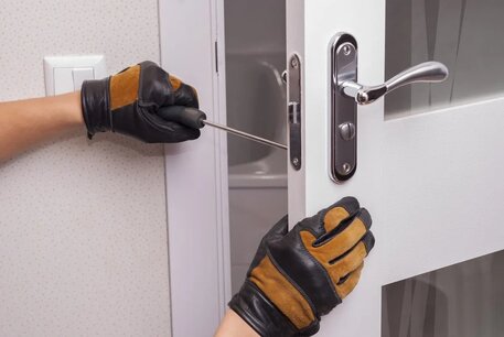 Detalle de una mano enguantada instalando una cerradura de puerta.