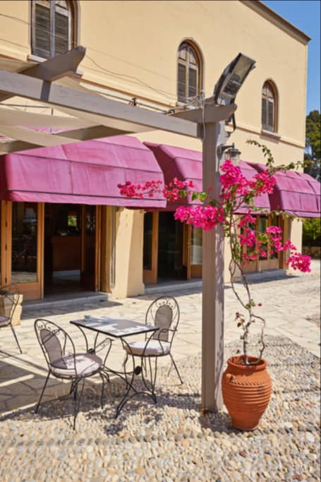 Toldo sobre una fachada comercial con mesas exteriores.