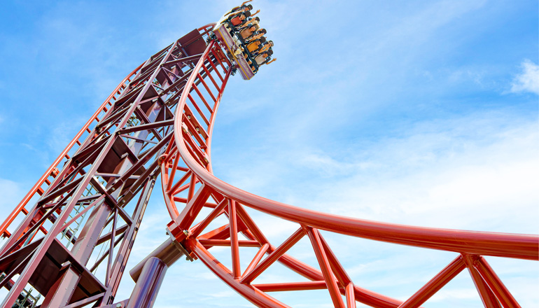 Montaña rusa roja que asciende por una estructura elevada en Paultons Park.