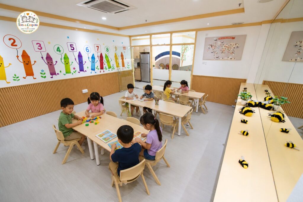 Aula de Tots & Crayons con mesas infantiles, materiales de aprendizaje y espacio para actividades en grupo.