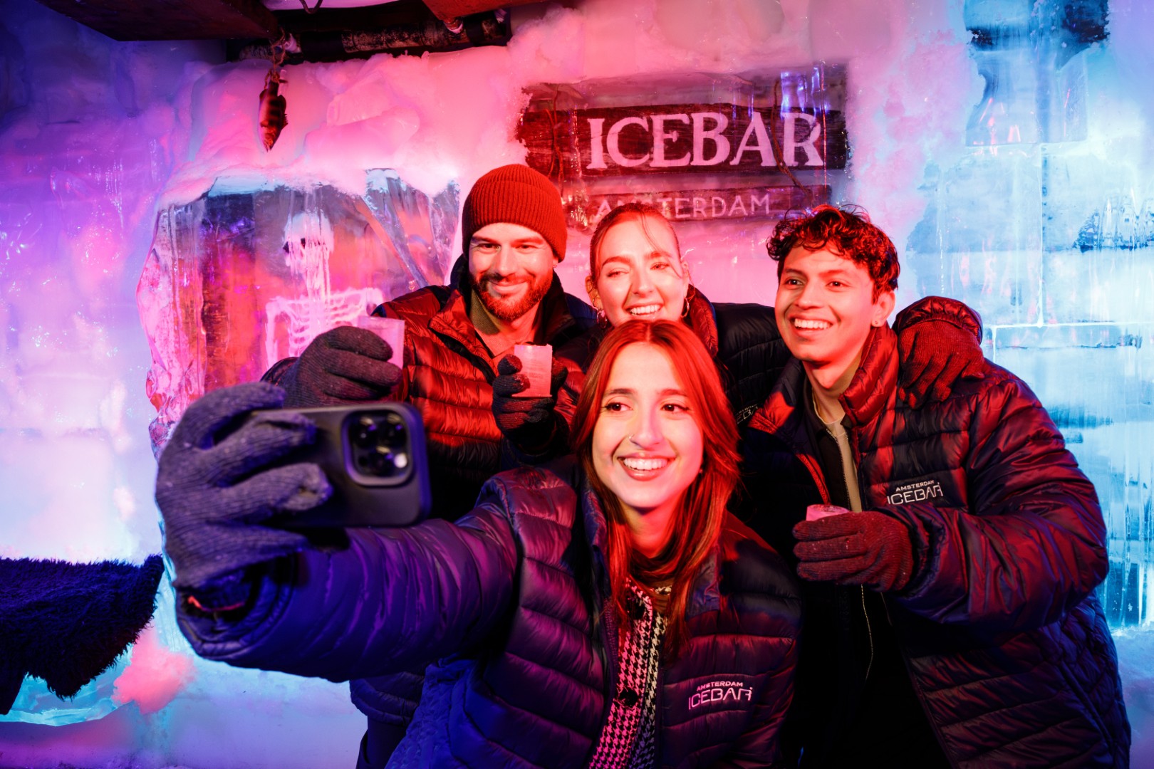 Visitantes con ropa térmica en la sala de hielo de Amsterdam Icebar, junto al letrero Icebar Amsterdam.