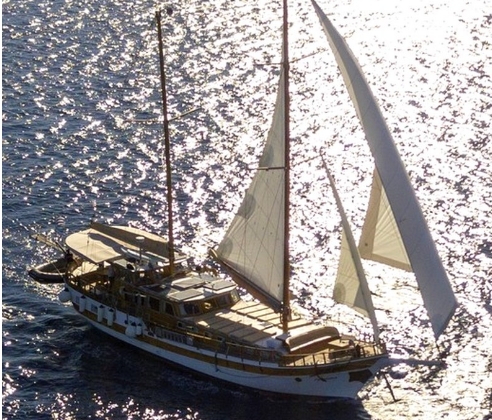 Velero tradicional de madera con las velas desplegadas durante una navegación.