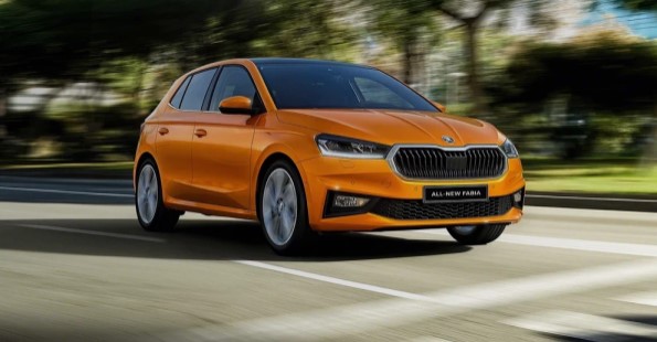 Orange ŠKODA car driving on a road.