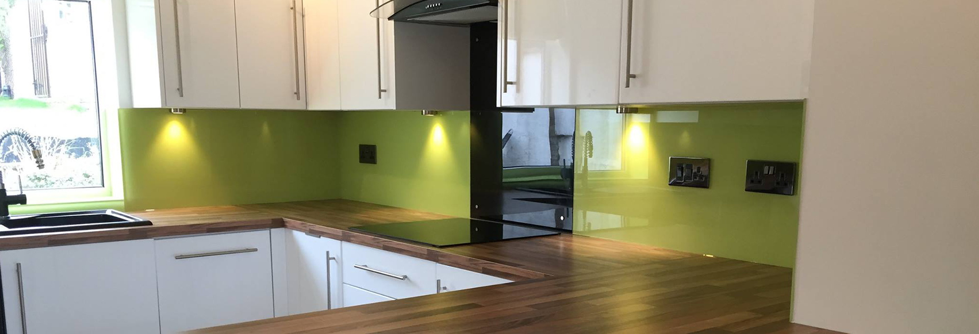 Cocina con panel de vidrio verde sobre la encimera. / Kitchen with a green glass backsplash.