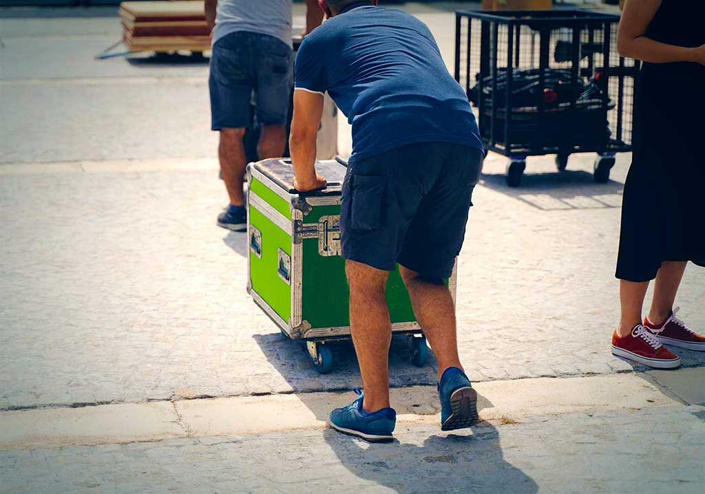 Dos personas trasladan una caja con un carro. / Two people move a box on a cart.