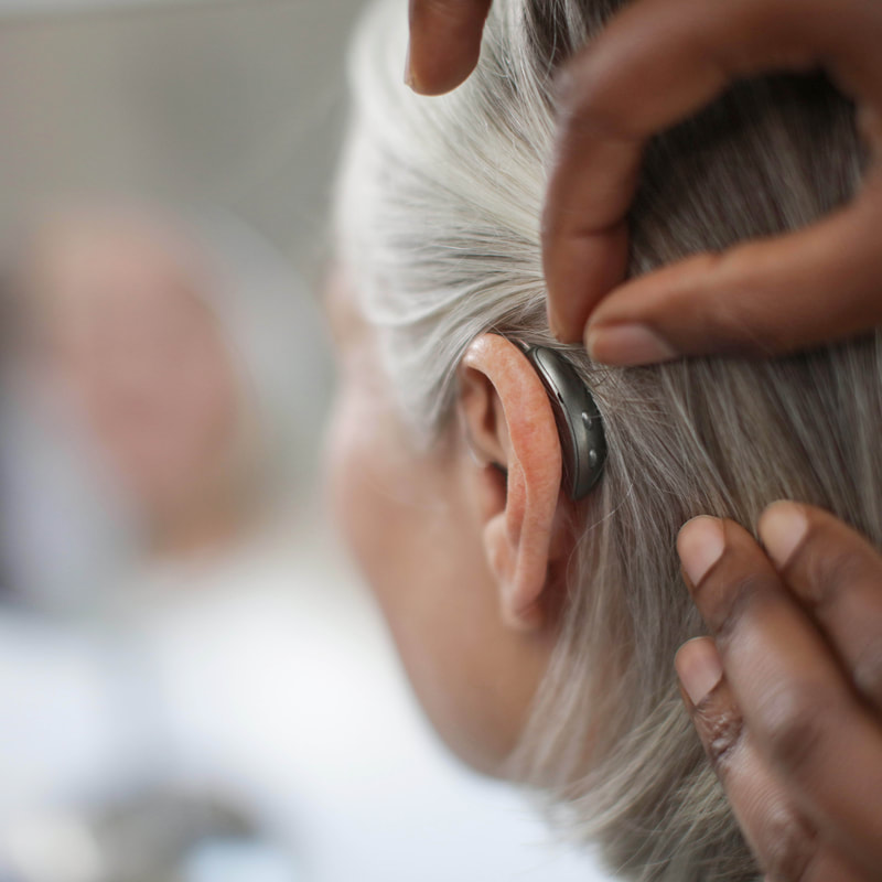 Audífono colocado detrás de la oreja durante una adaptación. / A behind-the-ear hearing aid shown during fitting.