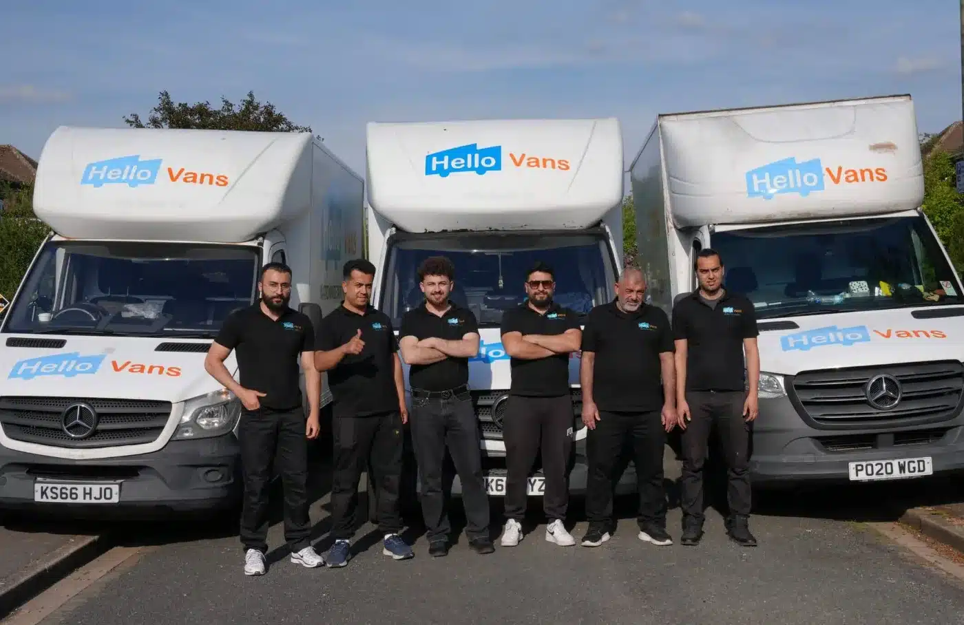 Equipo de Hello Vans posa frente a sus furgonetas de mudanza. / Hello Vans crew stands in front of branded moving vans.